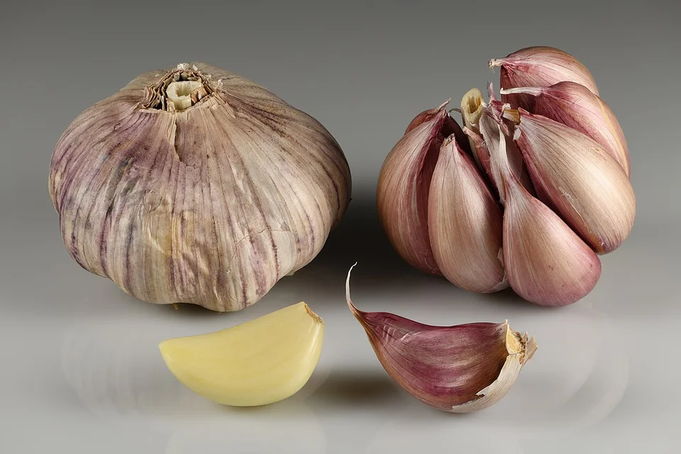 Whole garlic bulbs and several separated cloves with intact papery skins.